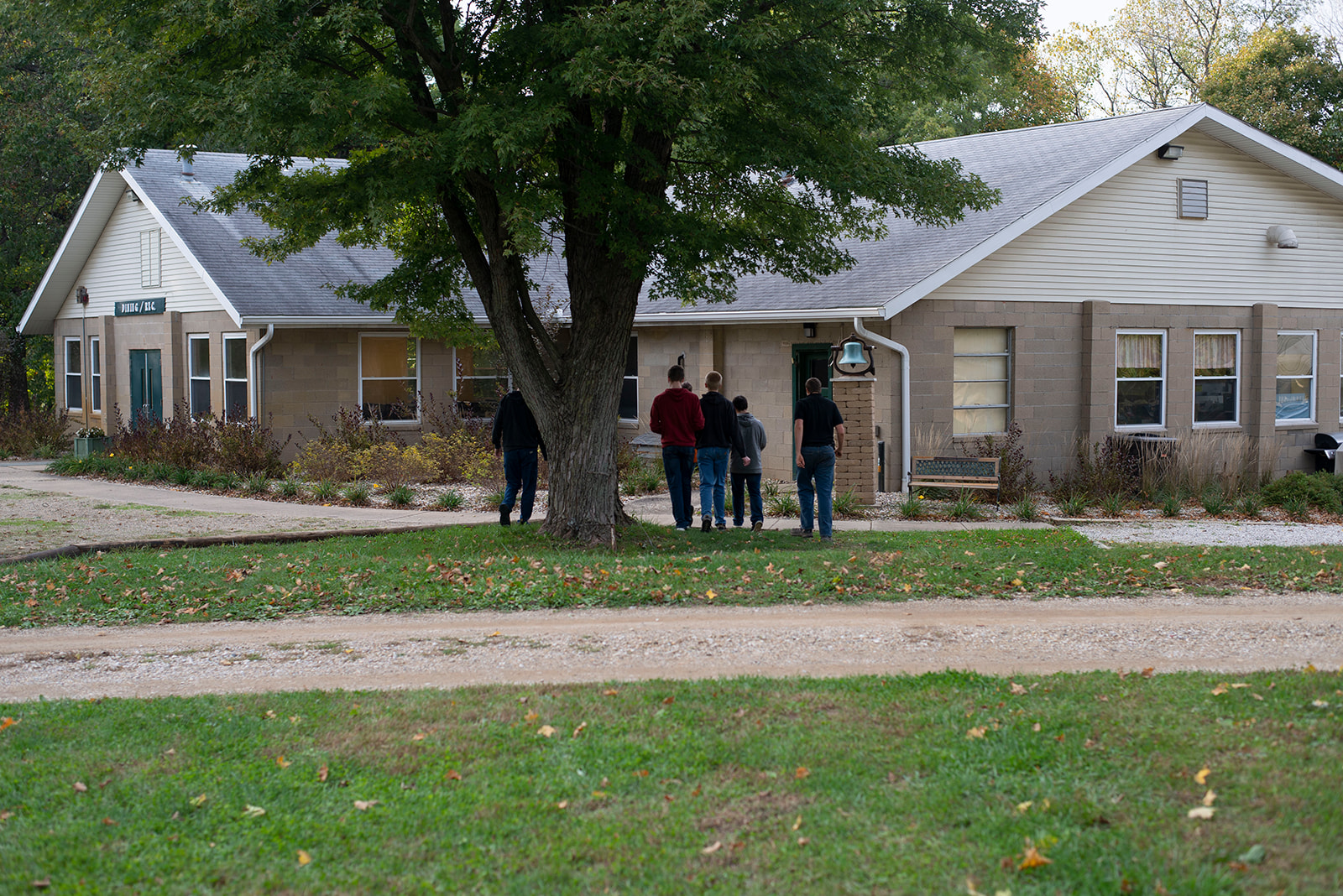 A group of men walk across a yard towards a building.